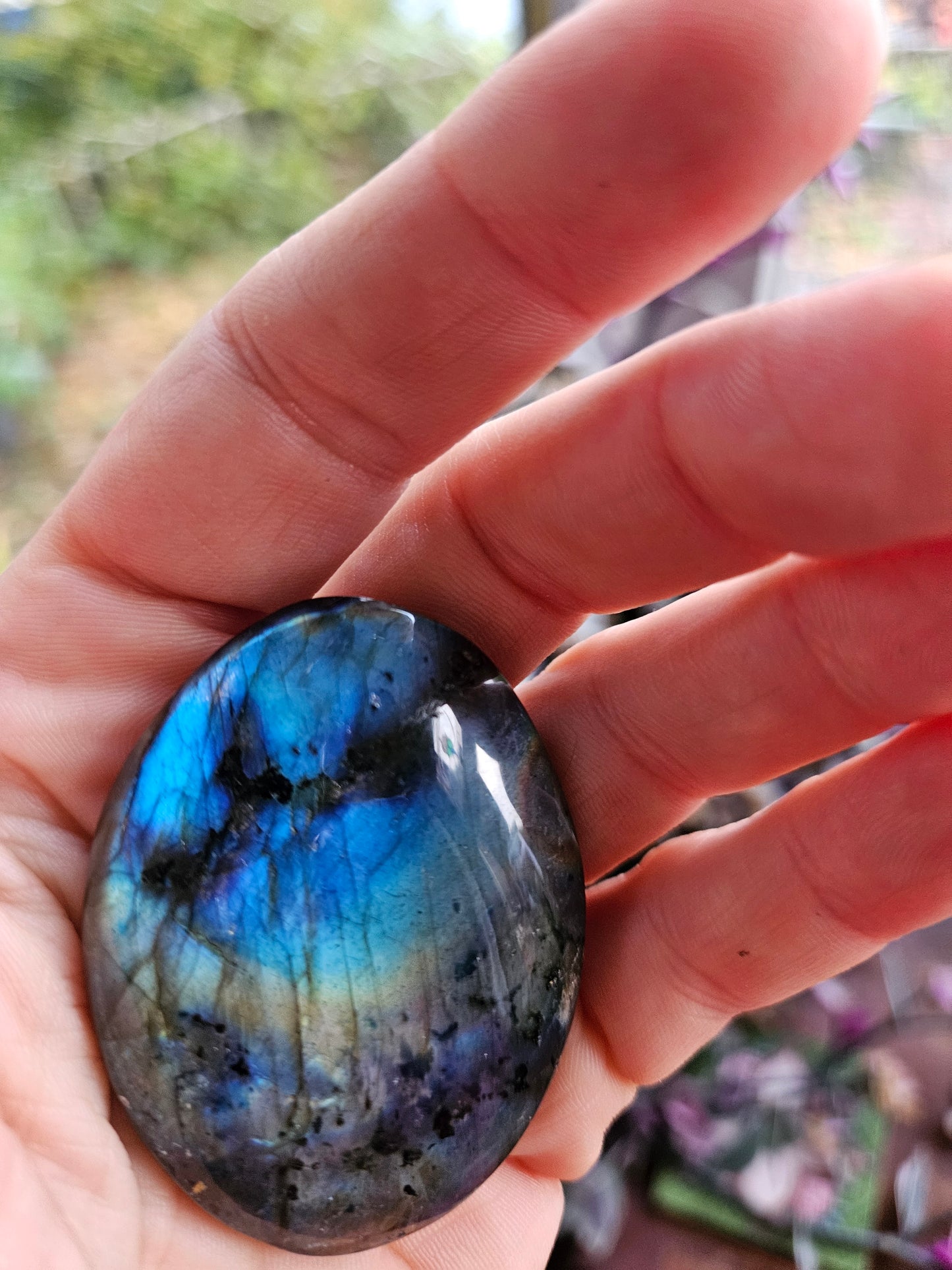Hand holding a labradorite stone with colorful reflections